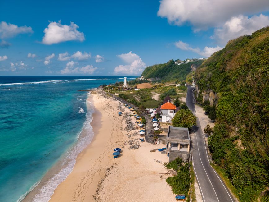 Aerial view of a Bali beach with a lighthouse and scenic coastline in Indonesia.