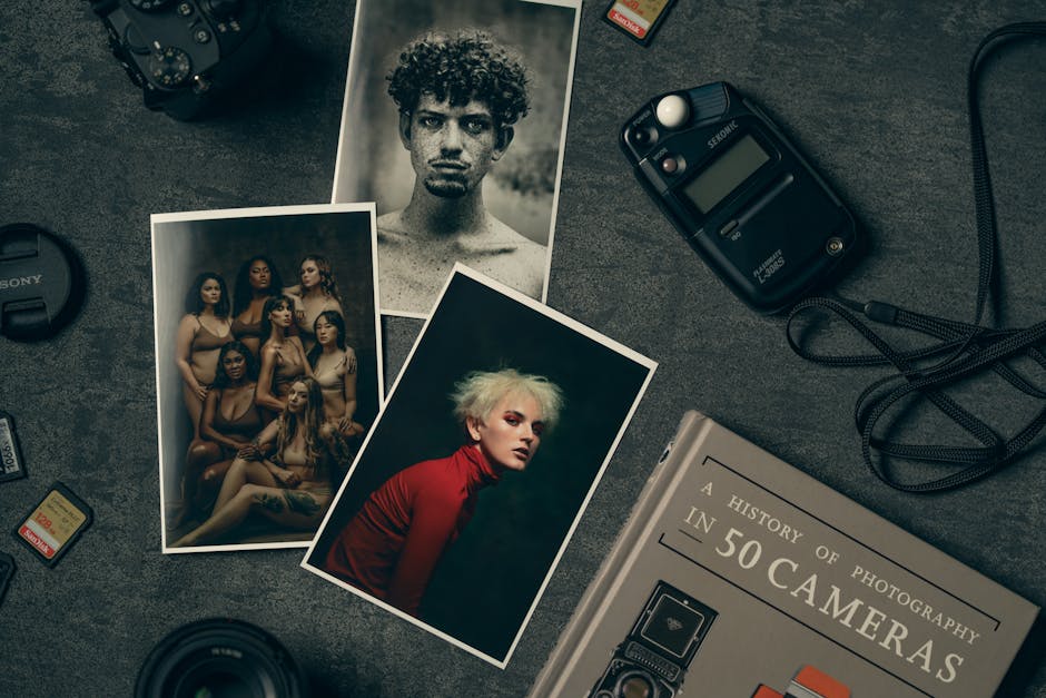 A creative photography desk setup featuring camera gear and diverse portrait prints.