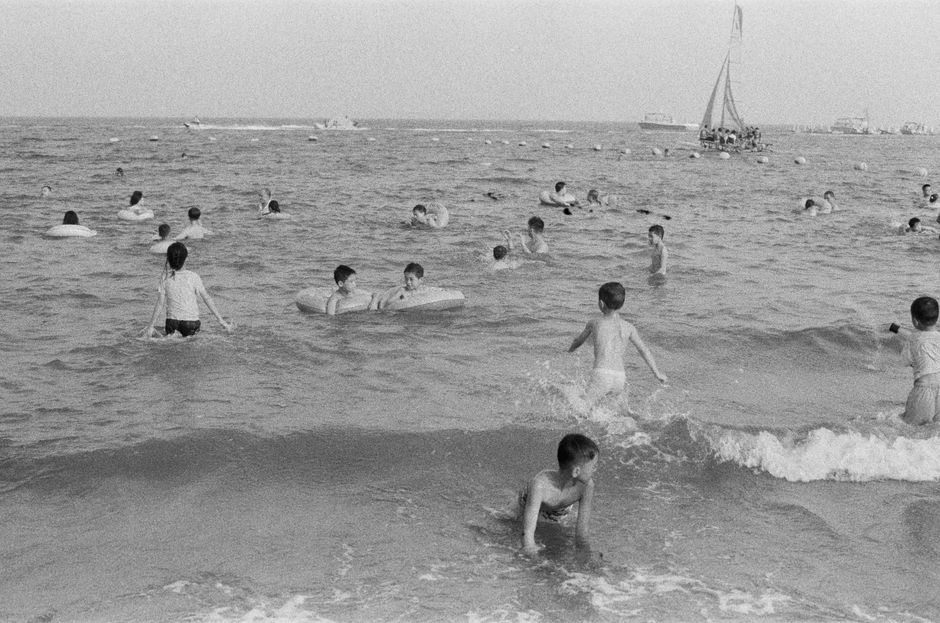 Black and white photo of children enjoying a day at the beach, playing in the ocean waves.