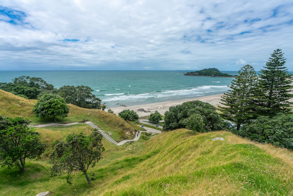 Breathtaking coastal landscape of Mount Maunganui, showcasing lush green hills, sandy shores, and vibrant blue sea.