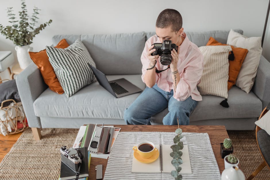 Unrecognizable concentrated female photographer with short hair taking picture of photography composition with cup of tea and green branch on table