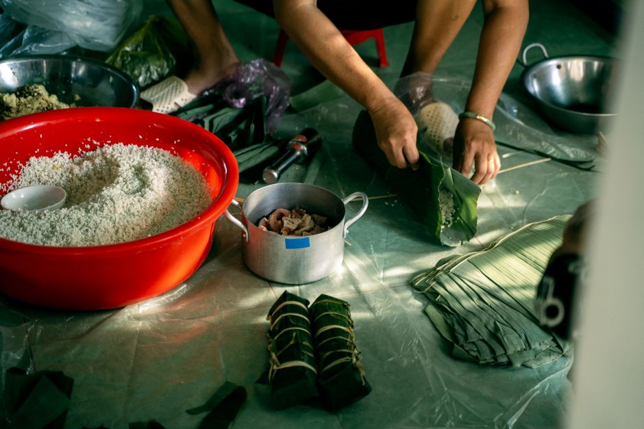 Hands wrapping ingredients with banana leaves to make Banh Tet.