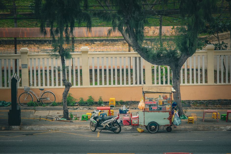 Traditional Vietnamese street food cart in Vũng Tàu cityscape setting.